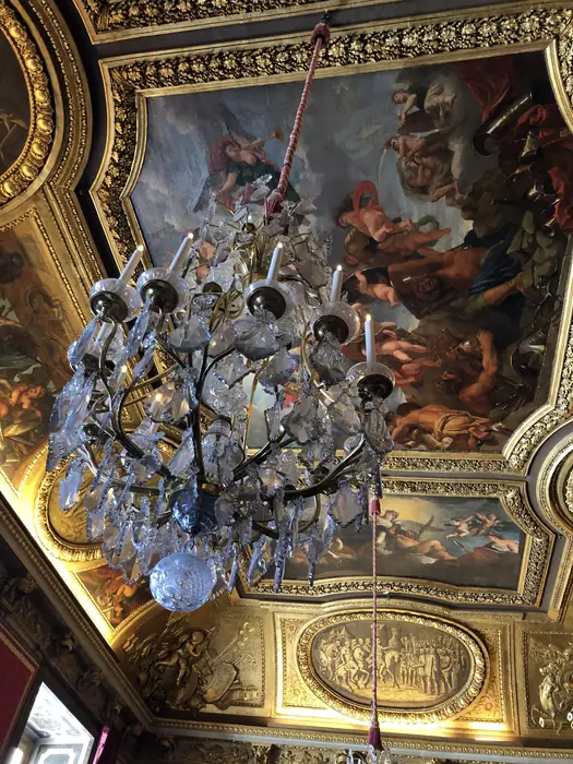 A crystal chandelier beneath a fresco of gods and heroes.