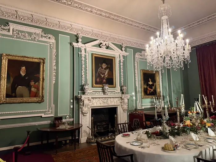 The Dining Room laid for dinner — green walls, white plaster, candlelight.